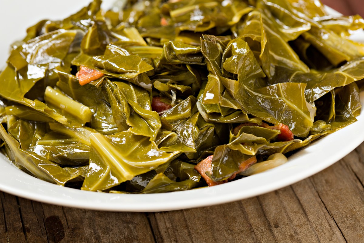 Crockpot cooked collard greens in a white bowl and prepared with ham hocks