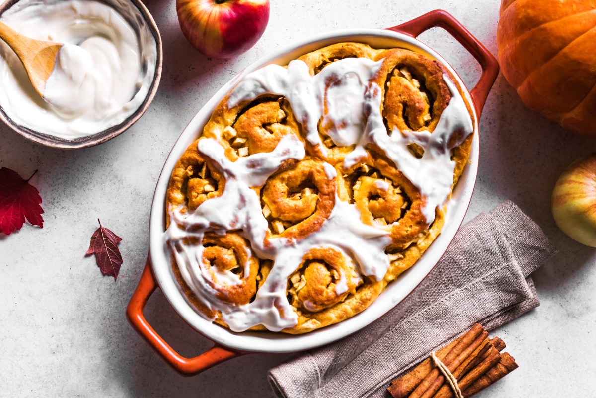 Pumpkin apples cinnamon rolls and organic pumpkins and apples close up. Seasonal autumn homemade pastry - cinnabons for breakfast.