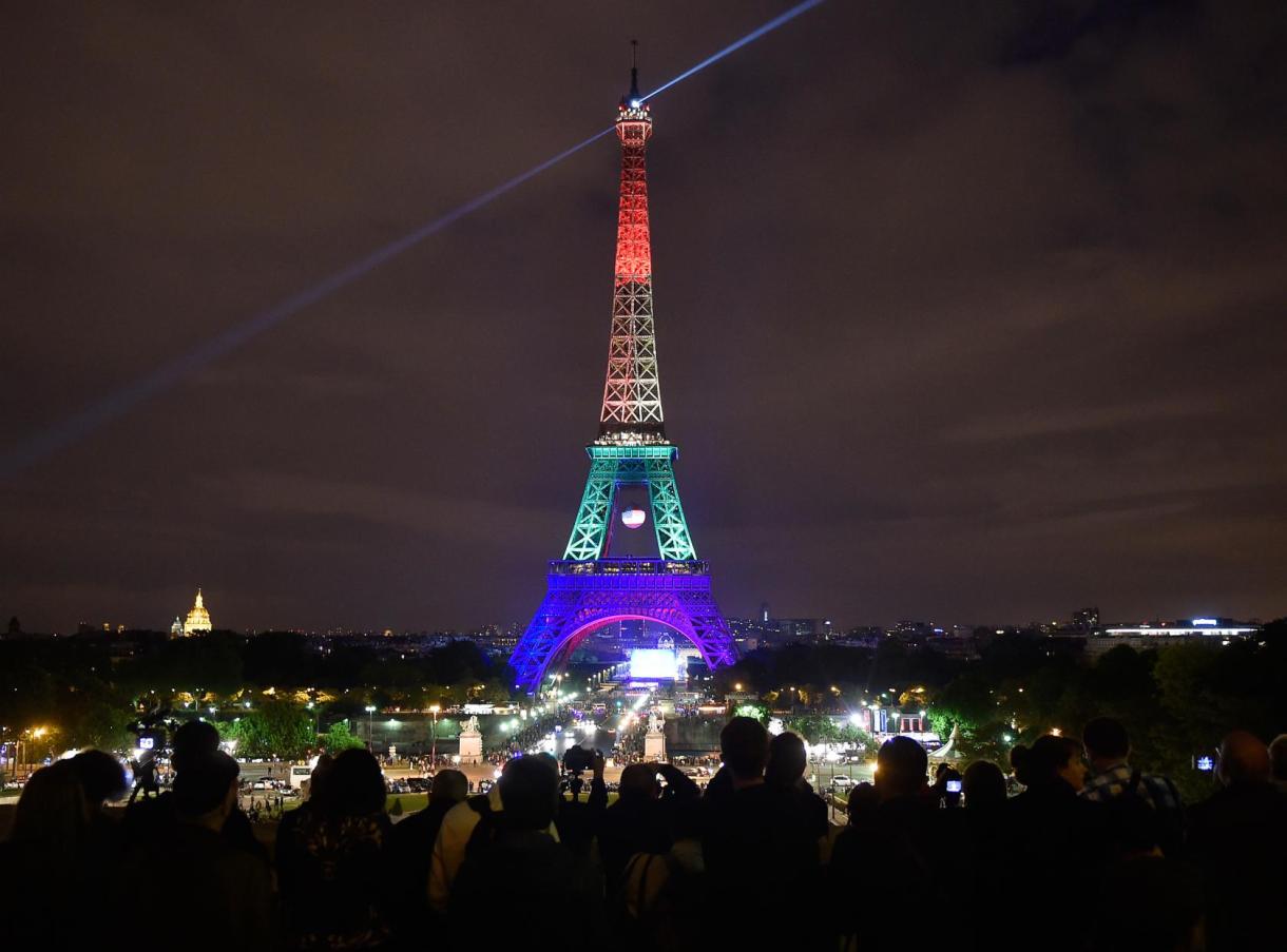 The Eiffel Tower in Paris, France, shines in the colors of a rainbow to honor victims of Sunday's mass shooting at an Orlando gay club, Monday, June 13, 2016. People brought banners, flags and candles to the Place Trocadero in front of the Paris landmark. (AP Photo/Martin Meissner)