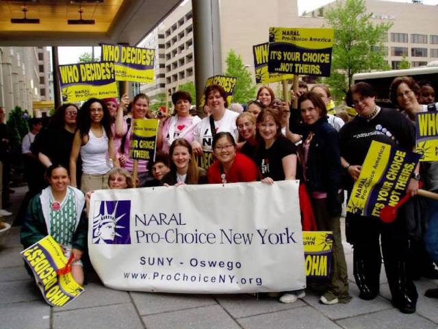 personal photo of the author with a group of 20 other activists from SUNY Oswego at the March for Women's Lives standing behind a NARAL Pro-Choice banner