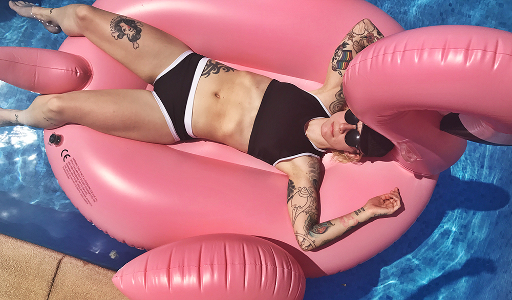 Girl laying in an Outplay Swimsuit on a Flamingo Float