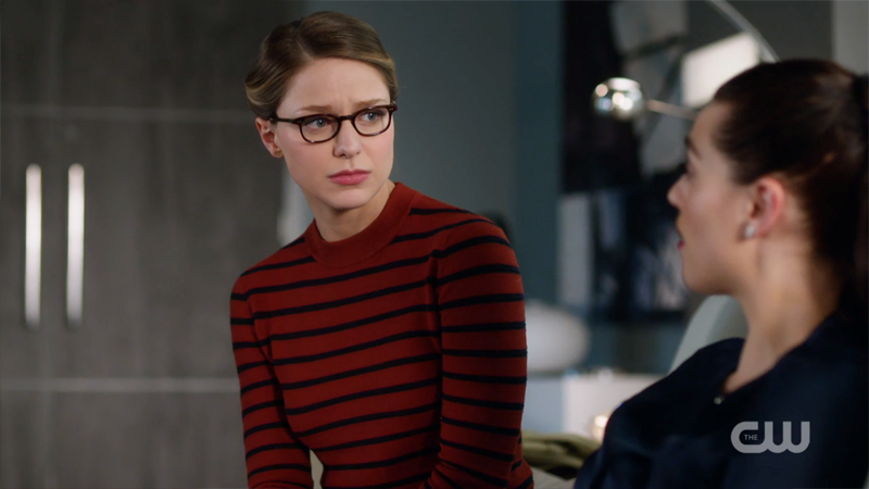 Kara sits on Lena's couch with a sympathetic look