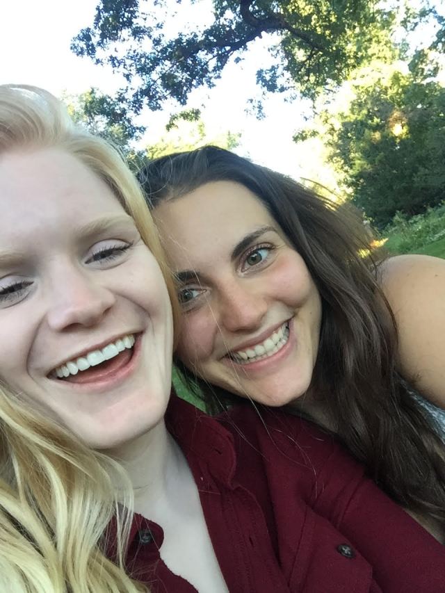 Lindy and Nicole smile at each other adorably in the park.