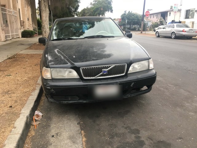 Photo of a black Volvo station wagon parked on a city street.