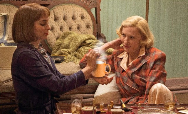 therese gives carol hot milk in an orange mug