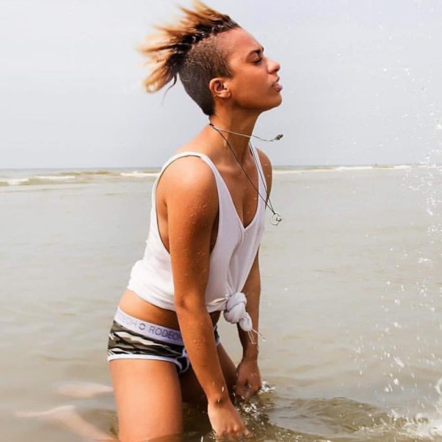 @filthy_versace in a knotted white tank top and camo harness, in the ocean