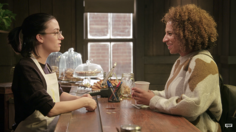 Claire and Nico talk over a coffee counter