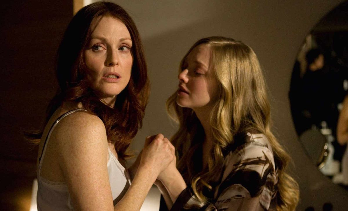 Amanda Seyfried holds Julianne Moore's hand and leans toward her as Moore looks away.