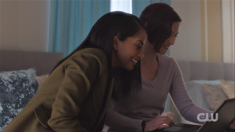 Kelly laughs over Alex's shoulder as they look at her computer