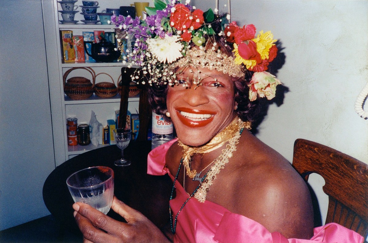 A glamour photo of Marsha P. Johnson in her famous flower crown and a pink dress.