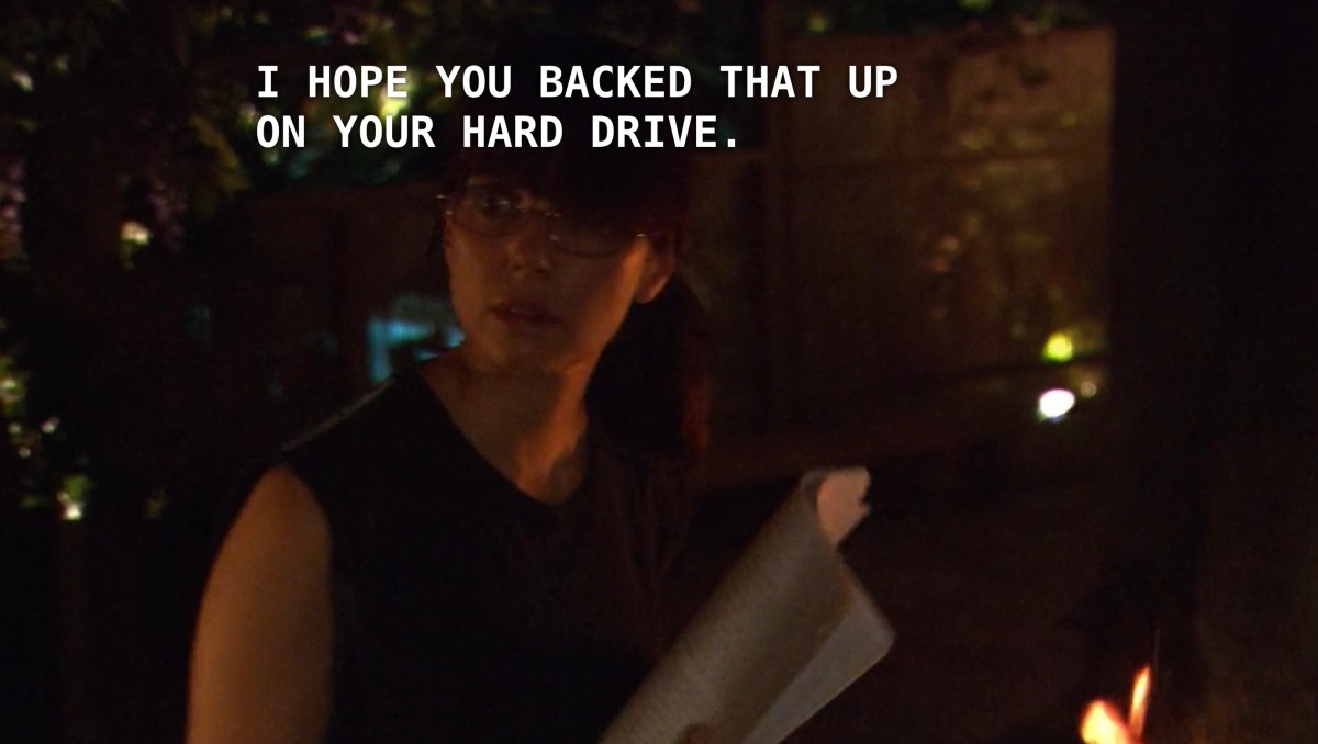 Jenny, wearing a black tank top and glasses with her hair in a ponytail, sits outside holding her manuscript as she adds page after page to a burning fire. Off screen, Max says, "I hope you backed that up on your hard drive."