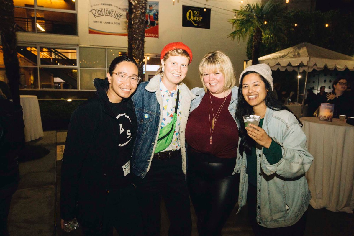 Four people pose for a photo outside.