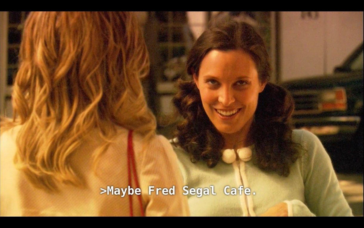 Dana (wearing pig tails and a light blue sweater) is looking at Alice (wearing a pink sweater, her back to the camera) with a sly look on her face. Dana says, "Maybe Fred Segal Cafe"