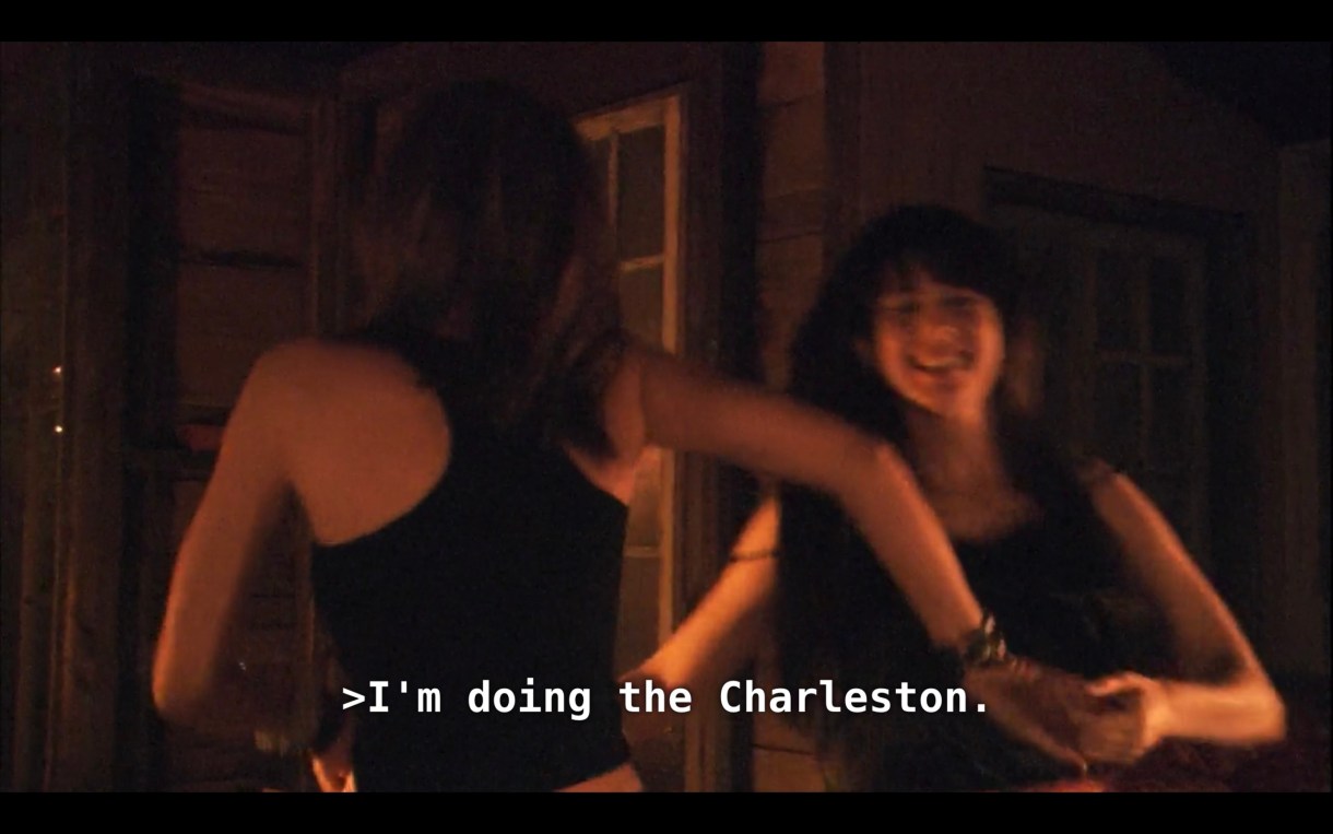 Dana and Jenny (both wearing black tank tops) are holding hands and dancing together in a dimly lit room. Dana says, "I'm doing the Charleston."