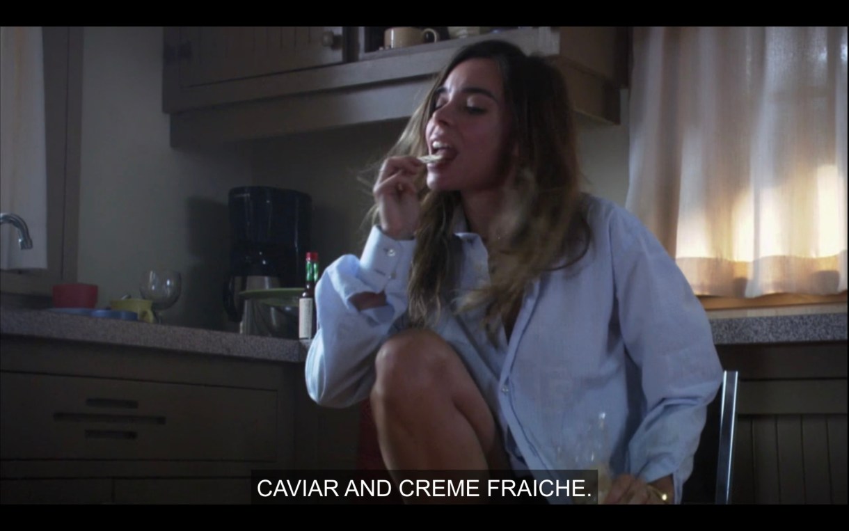 Claude licks the lid of a yogurt, subtitle says "Caviar and Creme Fraiche"