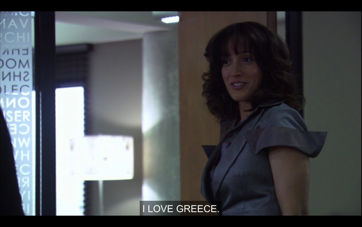 Bette stands in the doorway of her office. She says to one of her TAs (who is off screen), "I love Greece."