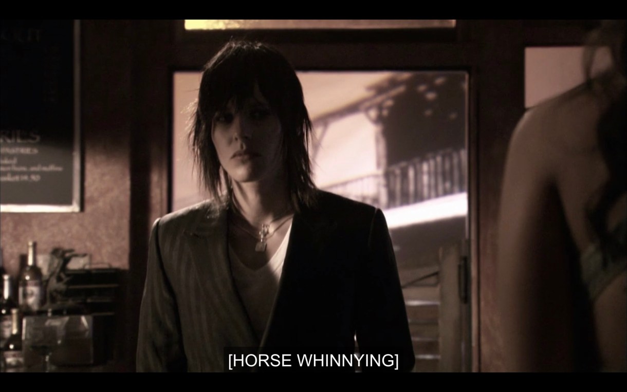 Black and white shot. Shane walks into The Planet. Subtitles read "[horse whinnying]"