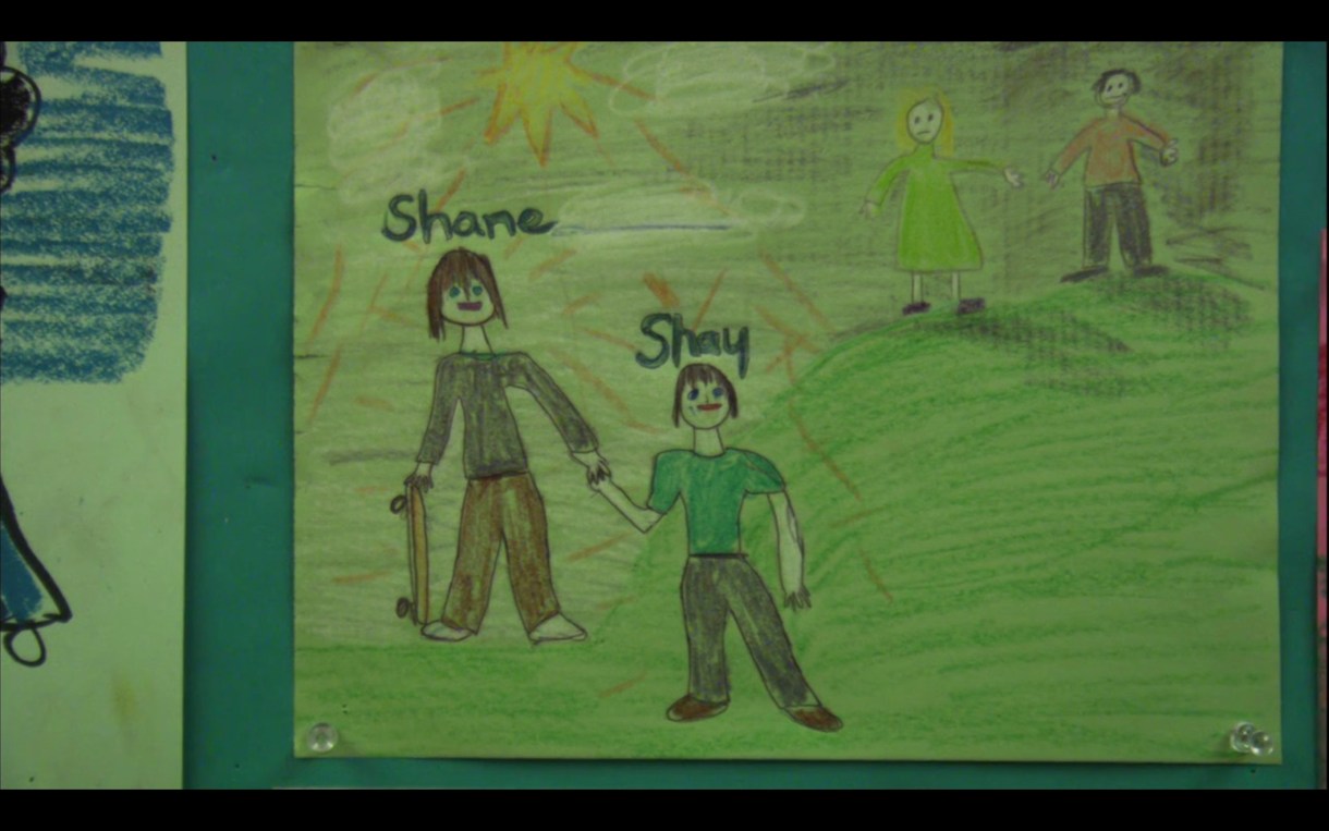 A drawing that Shay drew of his family. In the picture, Shane has a skateboard and is holding hands with Shay. Off in the corner are Shay's mom and dad.