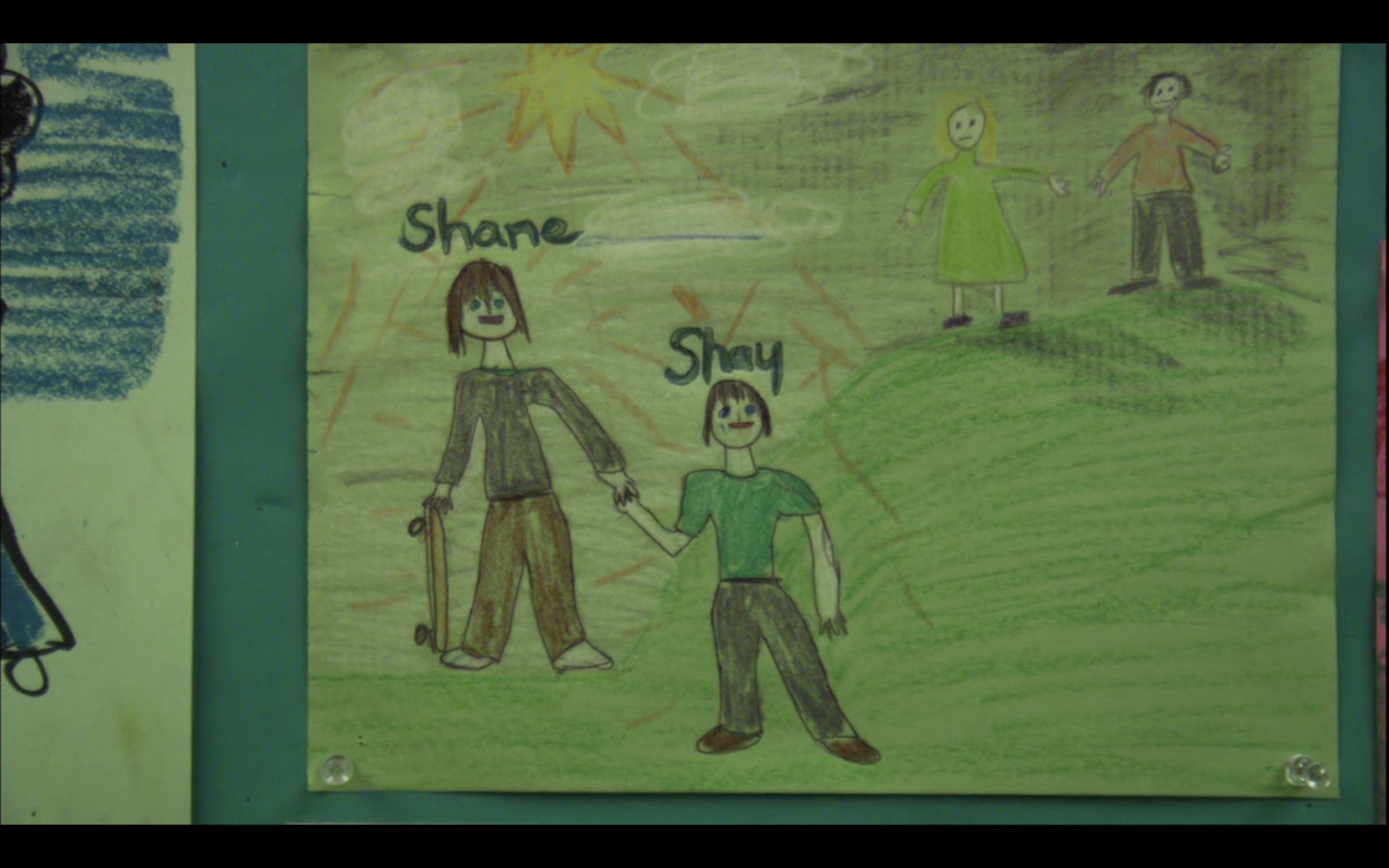 A drawing that Shay drew of his family. In the picture, Shane has a skateboard and is holding hands with Shay. Off in the corner are Shay's mom and dad.