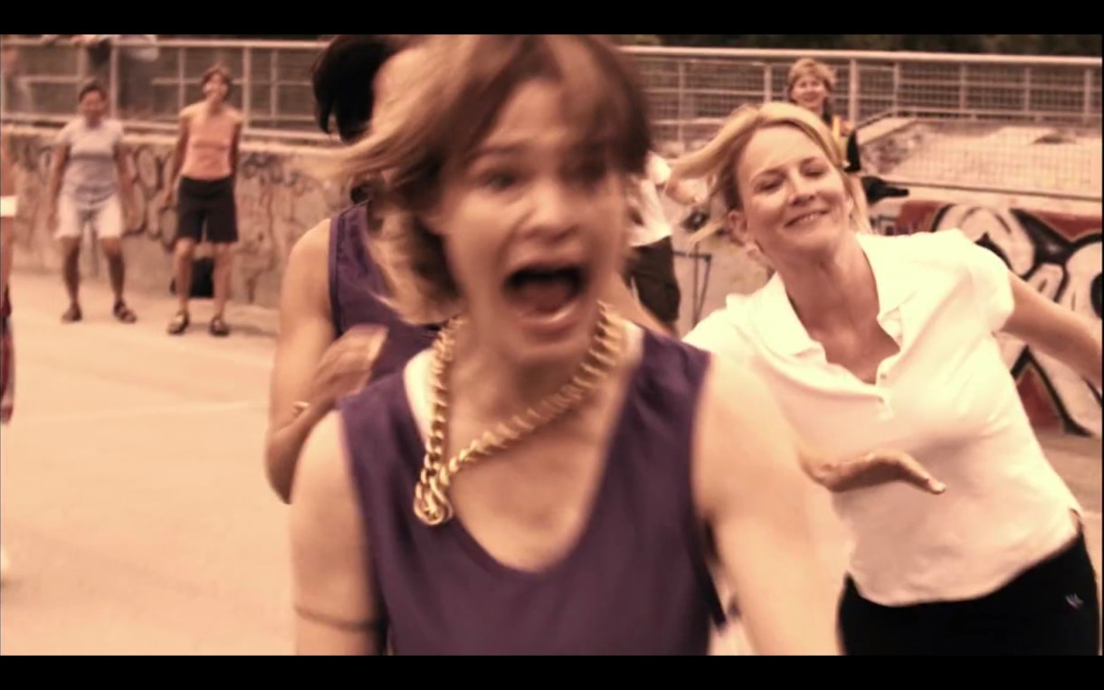 Alice (in a purple basketball jersey) mid-scream on the basketball court. Tina (in a white polo shirt) is running behind her. 