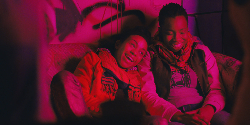 Two girls laughing in a red-lit room.