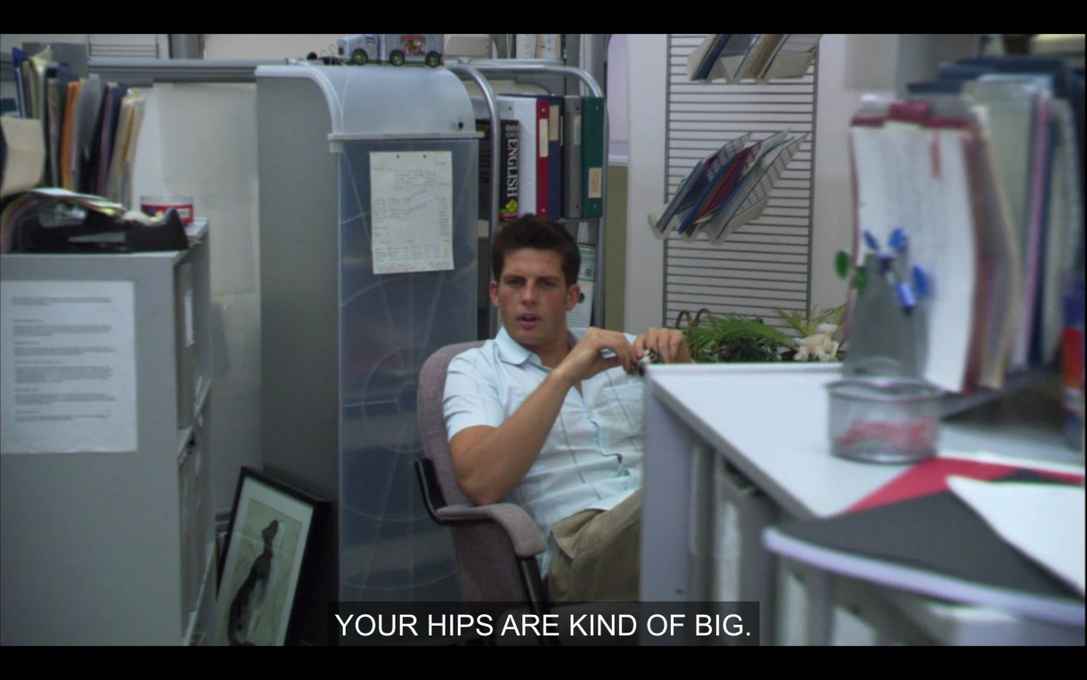 In a boring office, a dude is leaning out of his cubicle to say "Your hips are kind of big."