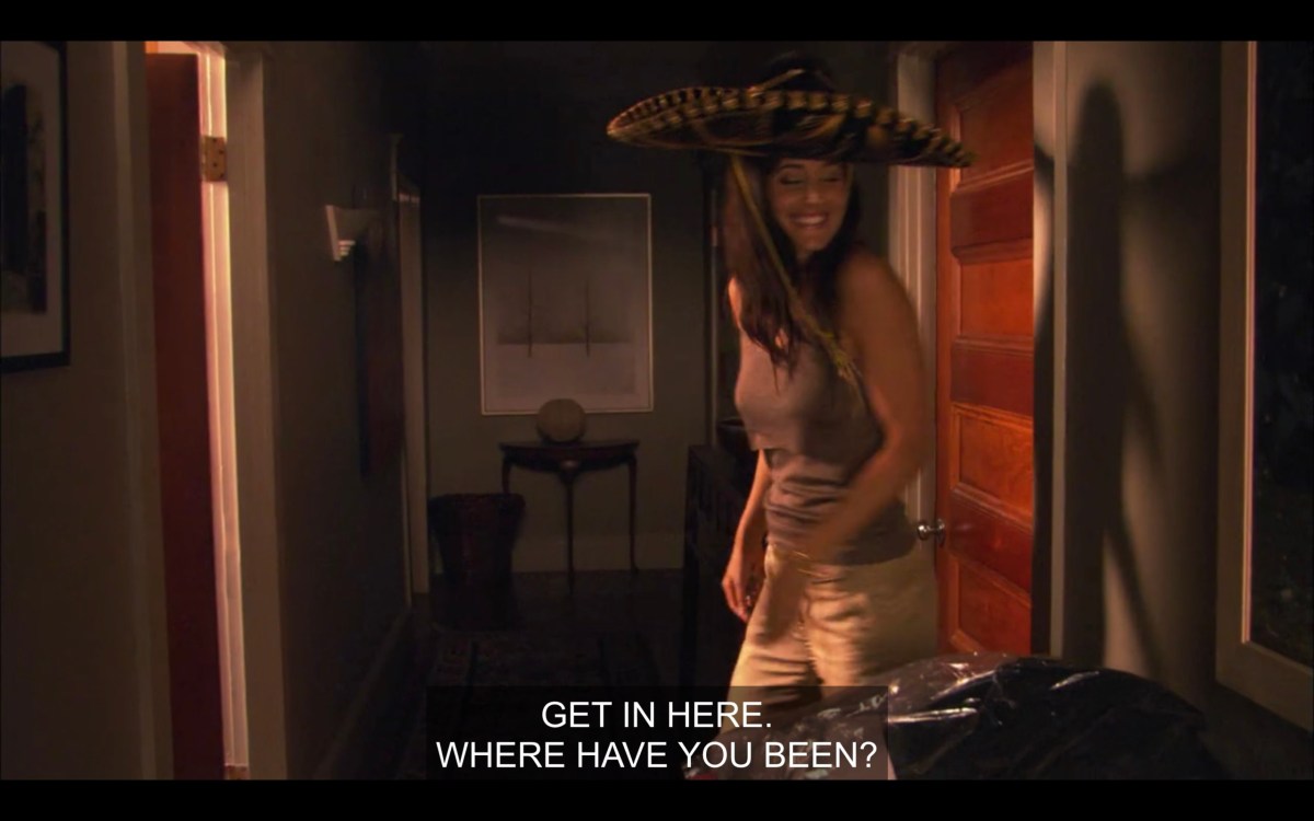 Helena wearing a big sombrero hat in Alice's apartment. She says, "Get in here. Where have you been?"