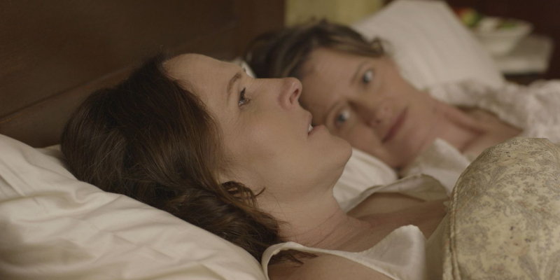 Molly Shannon lies in bed with another woman.