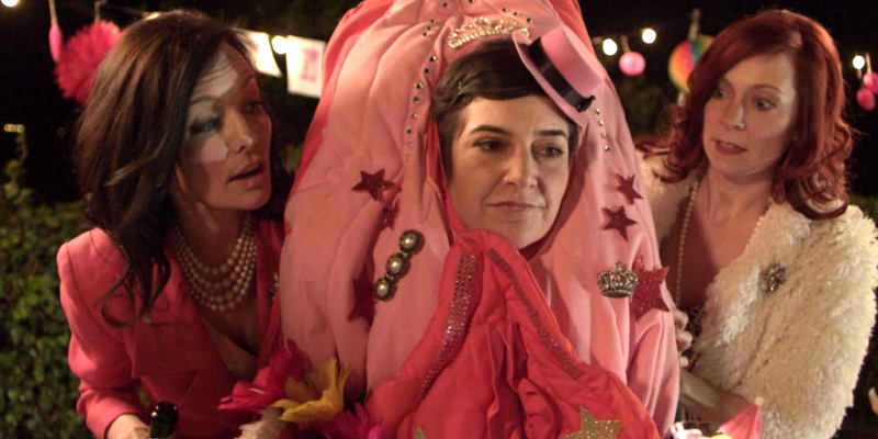 Anna Margarita Albelo wears a vagina costume as Guinevere Turner and another woman stand behind her.