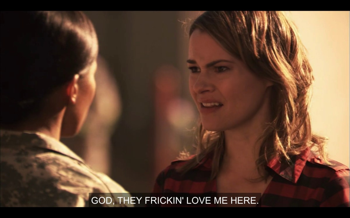 Alice (wearing a red and black flannel shirt) and Tasha (in her army uniform) facing each other. Alice says, "God, they friction' love me here."