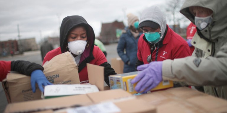 relief workers in masks helping unload boxes