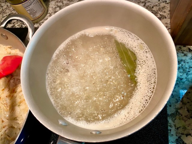 a pot of rice with a roiling boil and a little peek of bay leaf visible through the bubbles