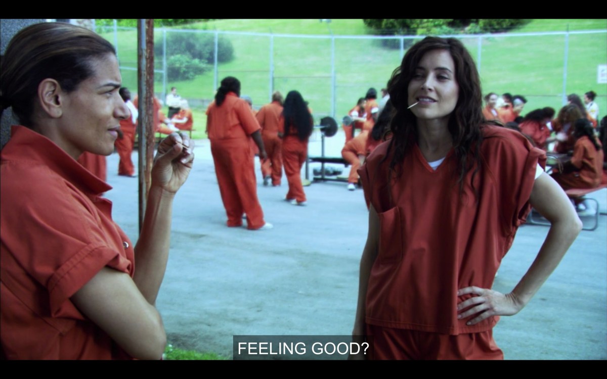 Helena in the yard at jail with a toothpick in her mouth, looking confident. The caption says "Feeling Good?"