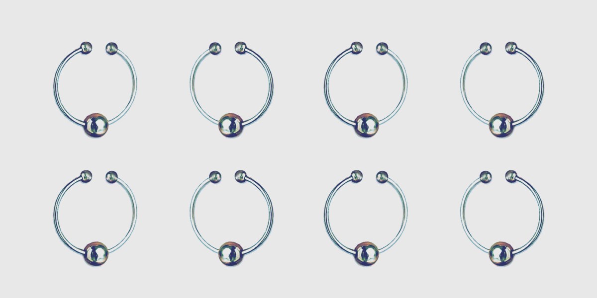 An array of small stainless steel nipple rings with an opening in ring to be worn or removed, and a single steel ball dangling on the hooped ring