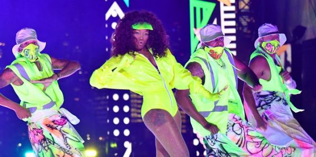 Keke Palmer performing on stage during this years MTV Video Music Awards. She is in a neon yellow leotard dancing with dancers in neon green masks and matching pants.