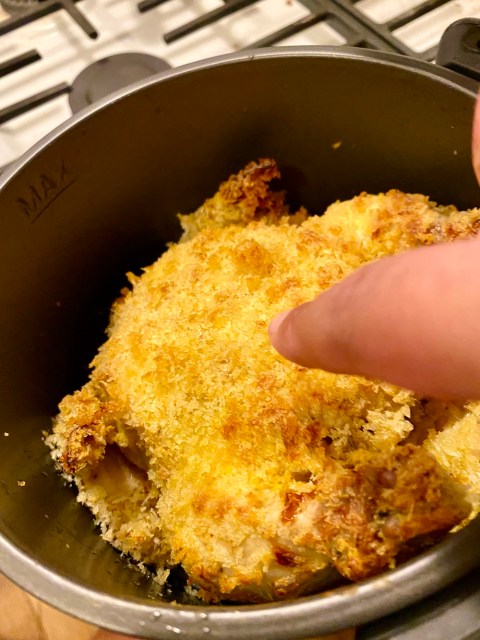 a finger pointing at the crispy, breaded outside of finished air-fried game hen