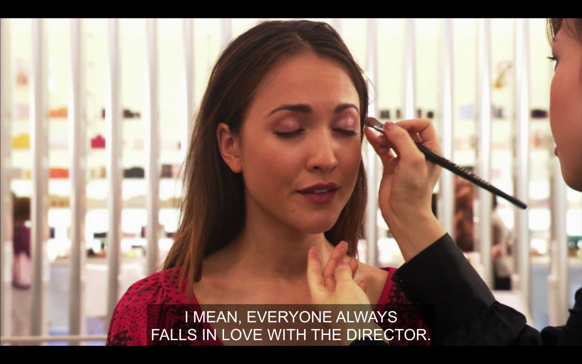 A makeup artist (not in the shot) does Adele's makeup while Adele says "I mean, everybody always falls in love with the director"