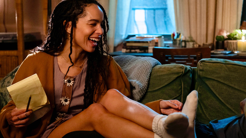 Rob (Zoe Kravitz) laughing on the couch in High Fidelity