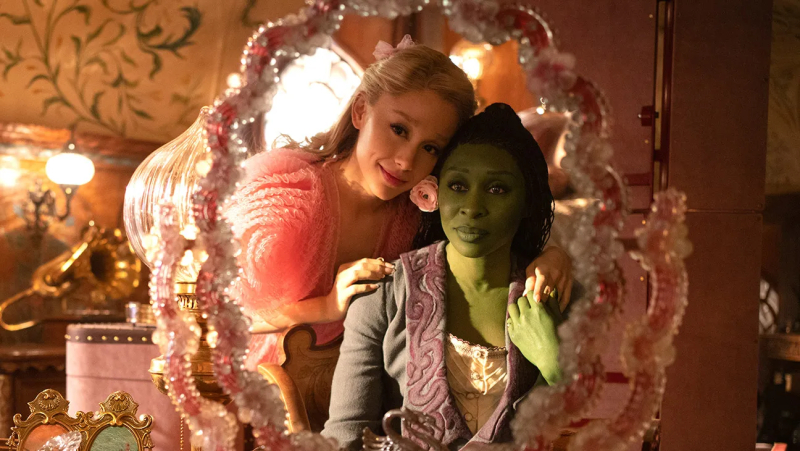 Ariana Grande and Cynthia Erivo look in a mirror together in Wicked