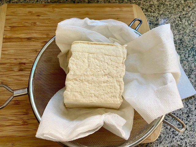 tofu in a strainer on top of paper towels