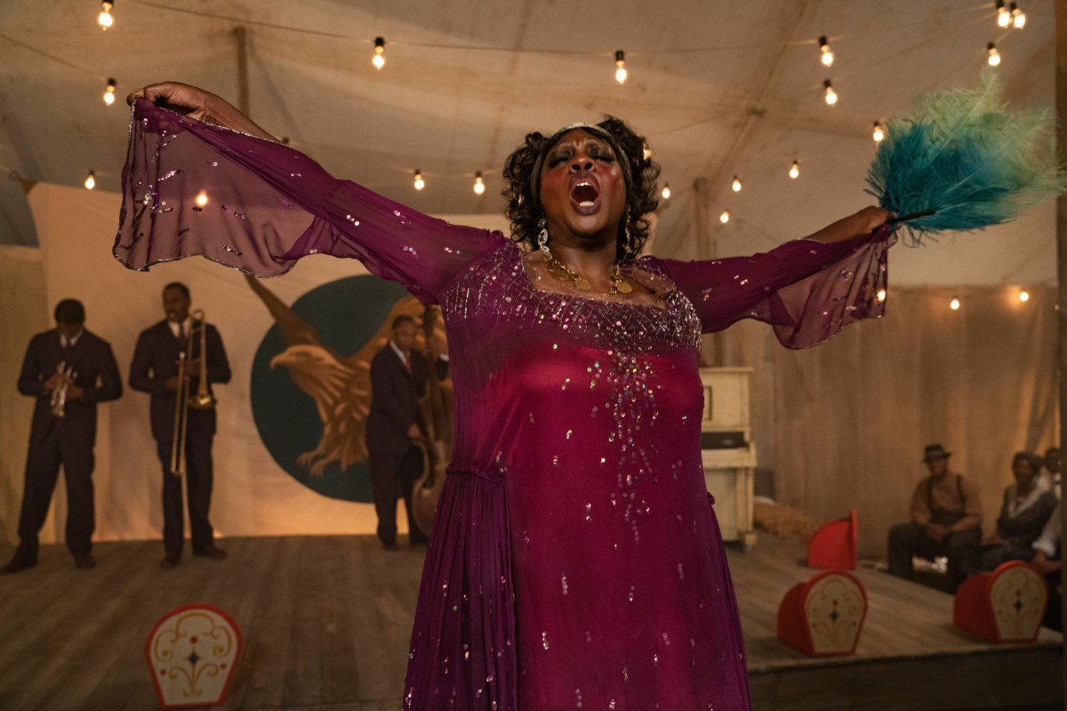 Viola Davis on stage in a shimmering purple dress and a blue feather