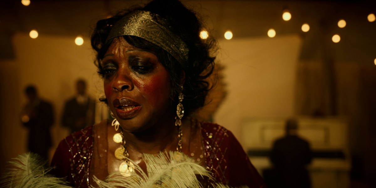 Viola Davis as Ma Rainey, in a gold headdress and a feather boa on stage.