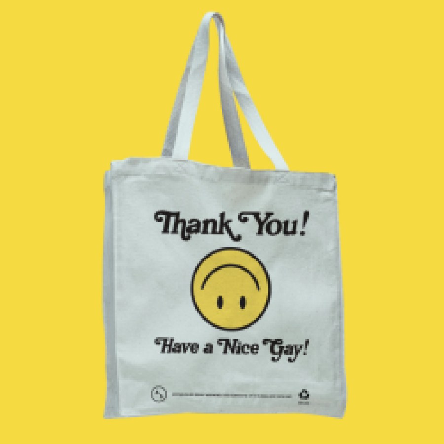 a white tote bag with an upside down yellow smiley face. The bag reads "Thank You Have a Nice Gay!"