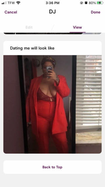 A mirror selfie of Dani wearing a red lace bodysuit and red blazer & trousers in her Hinge profile