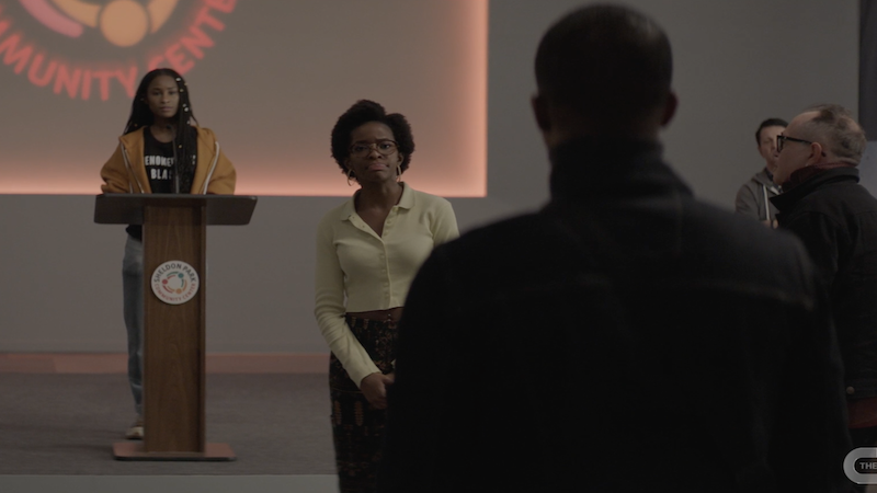 jordan and imani standing at the front of the room talking to a man whose back is to the camera