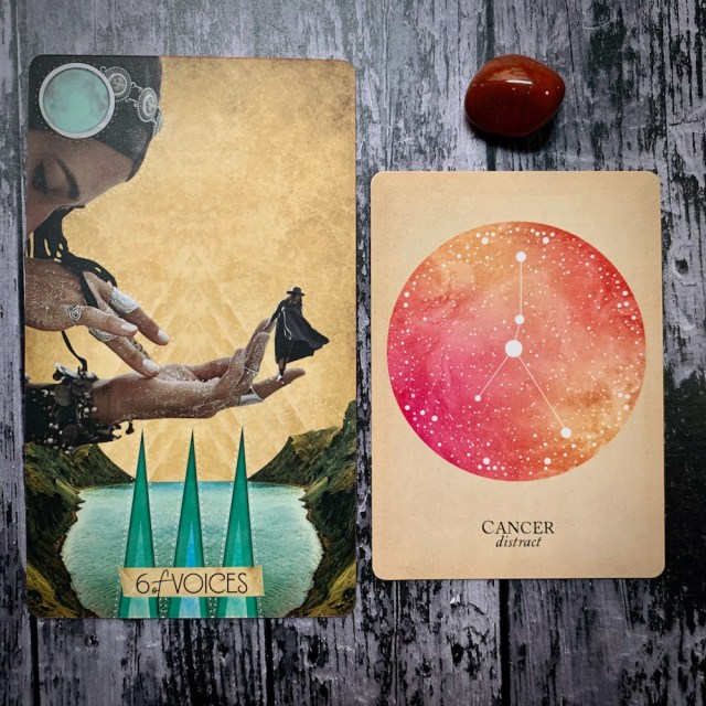 A tarot card for the 6 of voices, with a woman bowed over a body of water holding a small figure in her hand, a constellation card for Cancer: Distract; and a red crystal