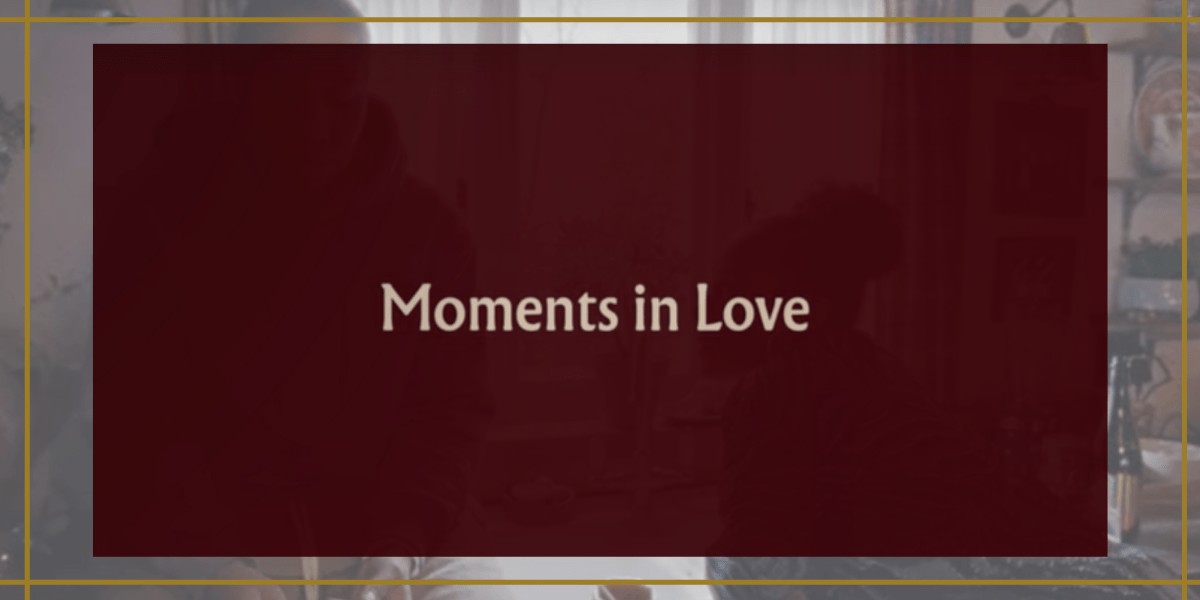 Image shows a burgundy box that has the words "moments in love" in the center with an image behind it that shows two people in a kitchen