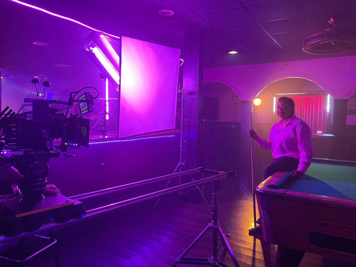 Sheila Smallman, owner of Herz lesbian bar in Alabama, sits on a pool table while being filmed for The Lesbian Bar Project