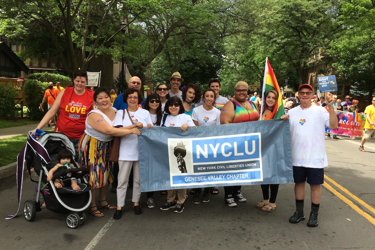 A group of people, including the author and her family, stands in the street, smiling and carrying a large sign for NYCLU