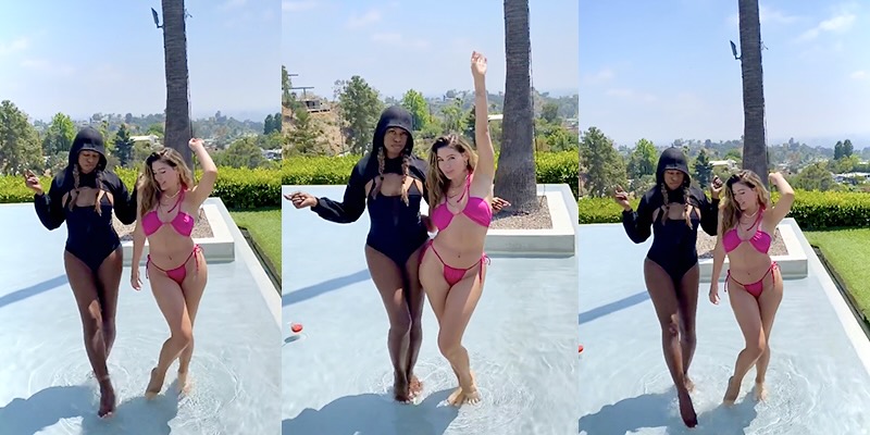 Laverne Cox and Trace Lysette dance together in bathing suits in a shallow pool and in front of a crisp blue sky